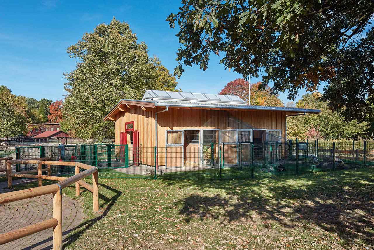 Neues Stallgebäude aus Holz mit offenen Stalltüren.