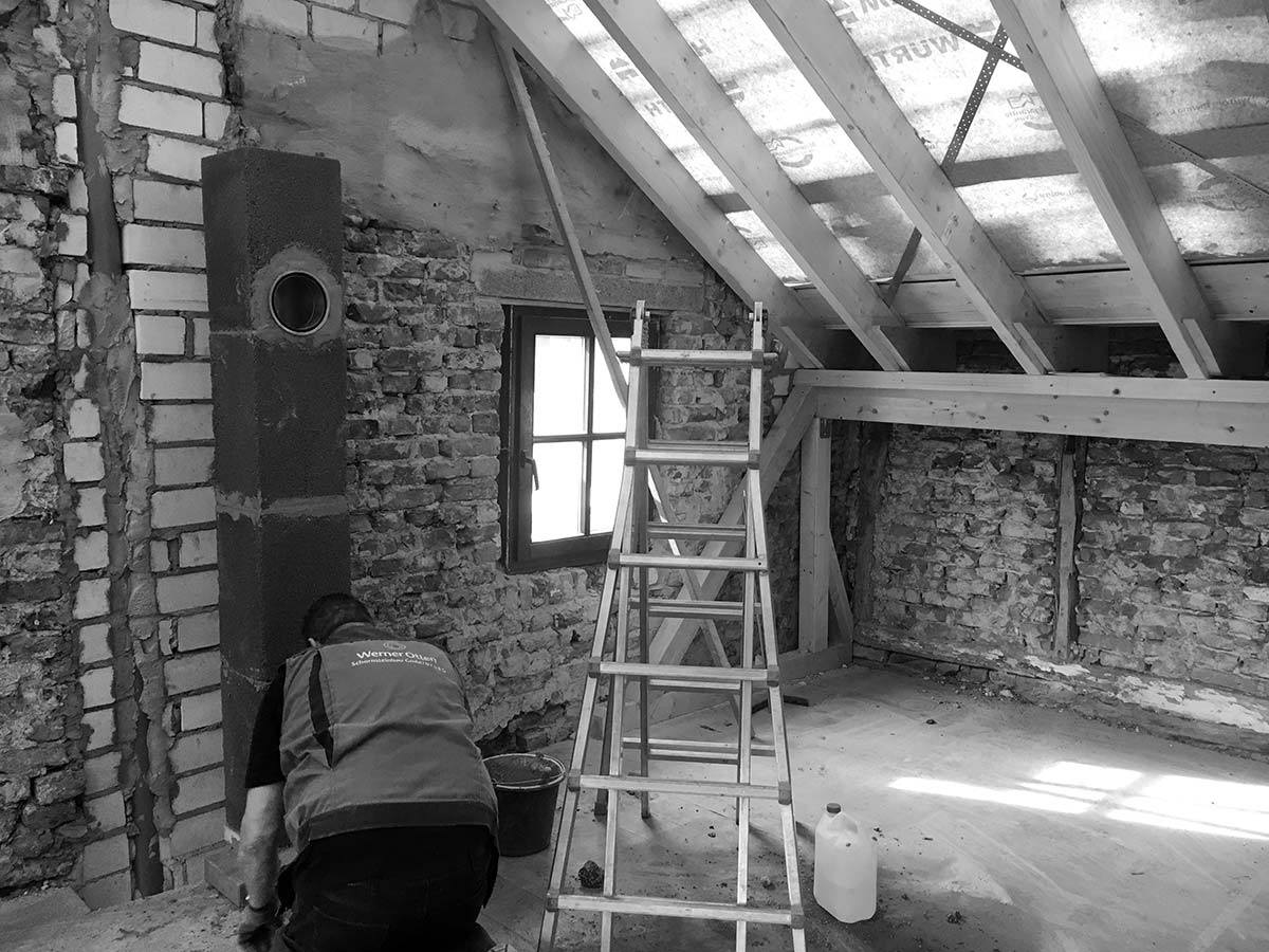 Ein neuer Dachstuhl wird auf ein altes haus gesetzt.