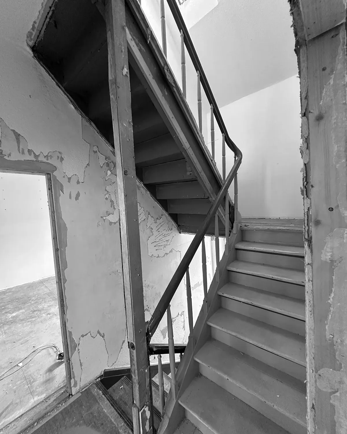 Treppenhaus während der Sanierung mit freigelegter Konstruktion, alten Stufen und unvollständigen Wandoberflächen.