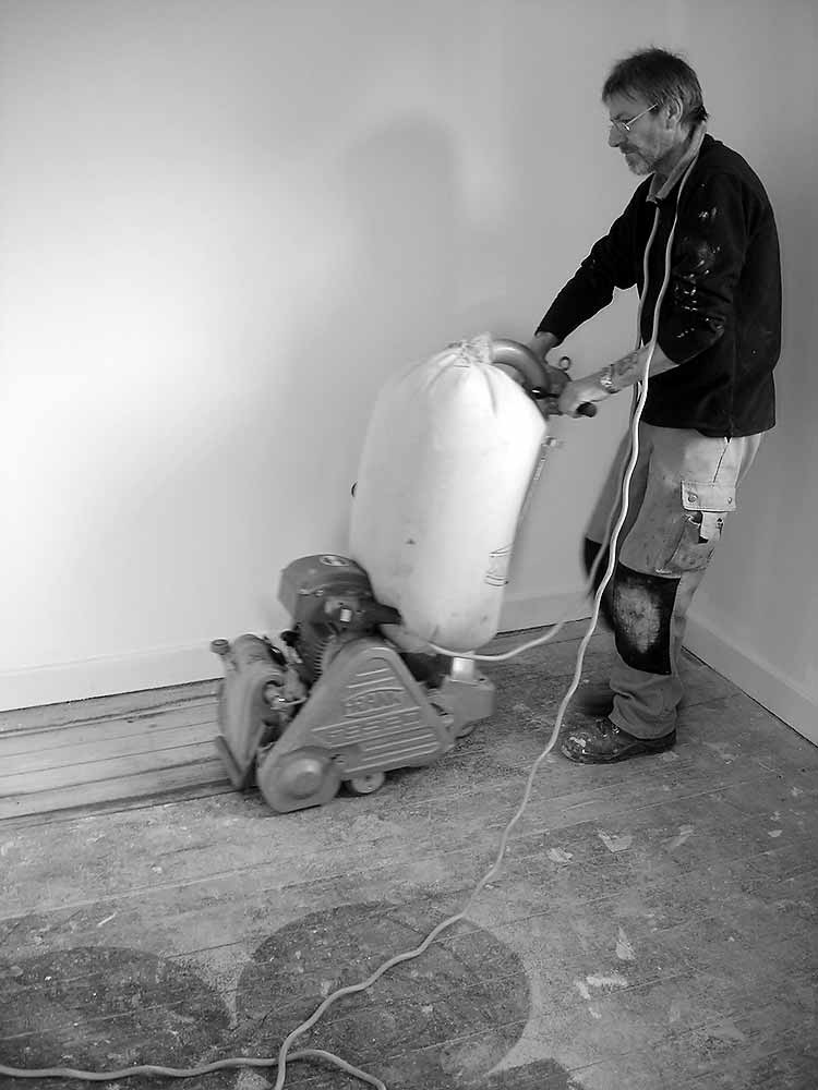 Arbeiter beim Abschleifen eines alten Holzbodens.